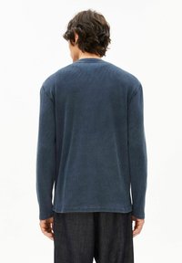 Langärmeliges, marineblaues Hemd mit geripptem Muster und Rundhalsausschnitt, mit entspannter Passform und geradem Saum, kombiniert mit dunkler Hose.