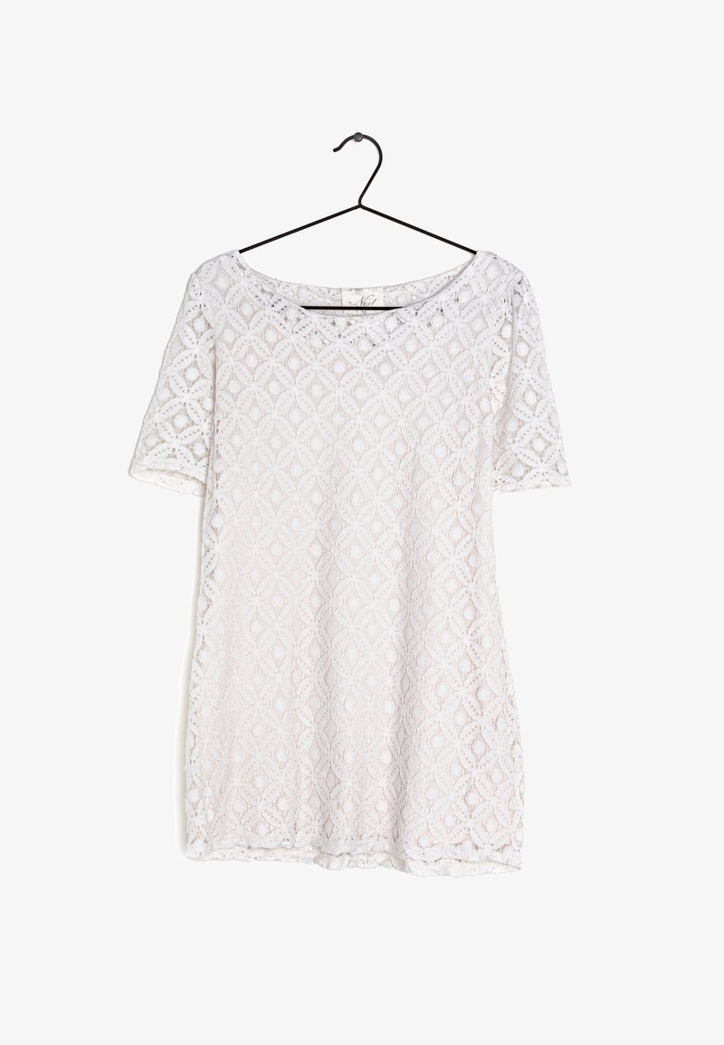 Robe blanche à manches courtes en dentelle avec un motif floral en losange, suspendue à un cintre noir sur fond blanc.