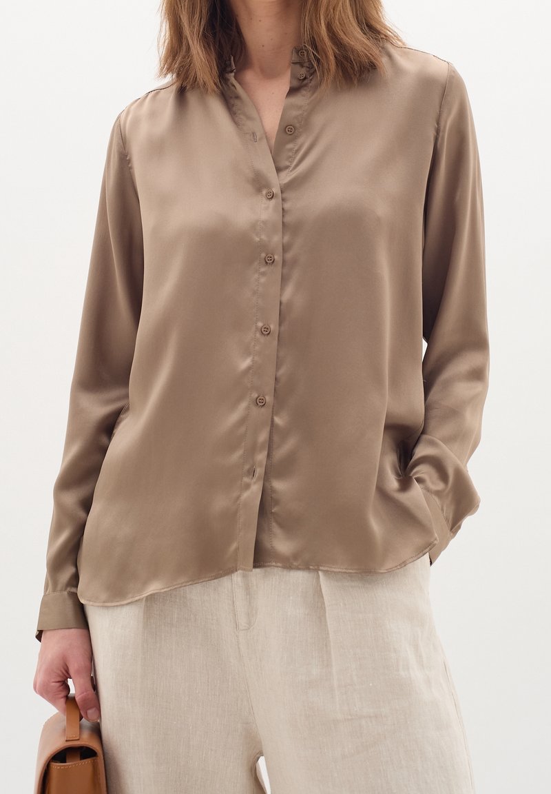 Long-sleeved, button-up blouse in light brown satin with a slight sheen. Features a mandarin collar and relaxed fit.