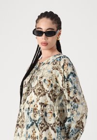 Μακρυμάνικο μπλουζάκι από ελαφρύ ύφασμα, με πολύχρωμο αφηρημένο σχέδιο σε μπλε, καφέ και κρεμ απόχρωσης και στρογγυλή λαιμόκοψη.