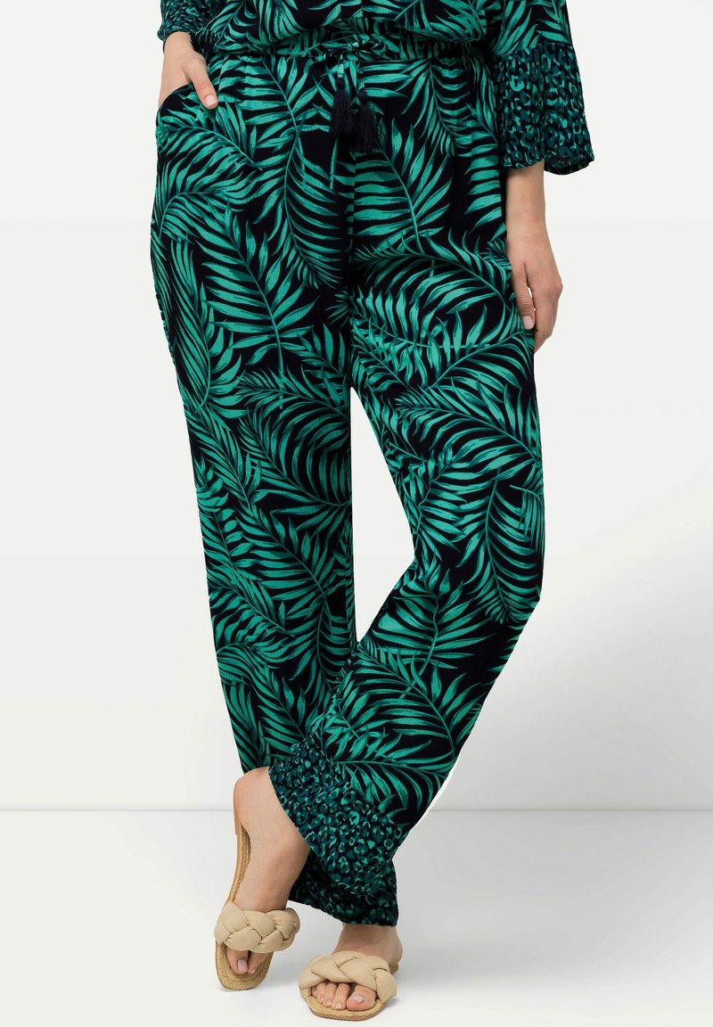 Svarta byxor med ett grönt lövmönster, tillverkade av ett lättviktigt tyg, med dragsko i midjan och en texturerad fåll.