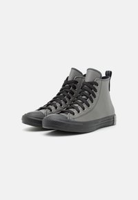 Sneaker alte grigie in tela con punta in gomma nera solida, lacci neri e suola testurizzata e flessibile.