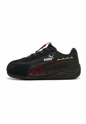 Zapatilla negra Puma con detalles rojos, panel lateral texturizado, toques verdes y logo Puma en el lateral, mostrada en vista lateral.