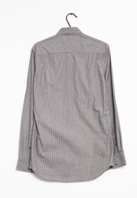 Hihaton paita harmaana, jossa on hienovaraiset raidat, napilliset hihansuut, klassinen kaulus ja suora helma. Kangas näyttää kudotulta ja teksturoidulta.