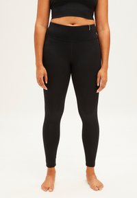 Zwarte leggings met een hoge tailleband, gemaakt van rekbaar materiaal, met een gladde textuur en naadloos ontwerp voor comfort en flexibiliteit.