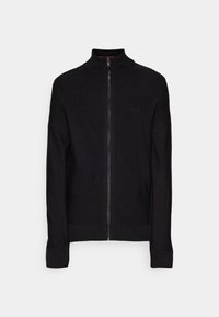 Svart zip-up-jacka i stickad tyg. Har en hög krage, ribbade muddar och fåll, med en diskret logotyp på bröstet. Slät textur.