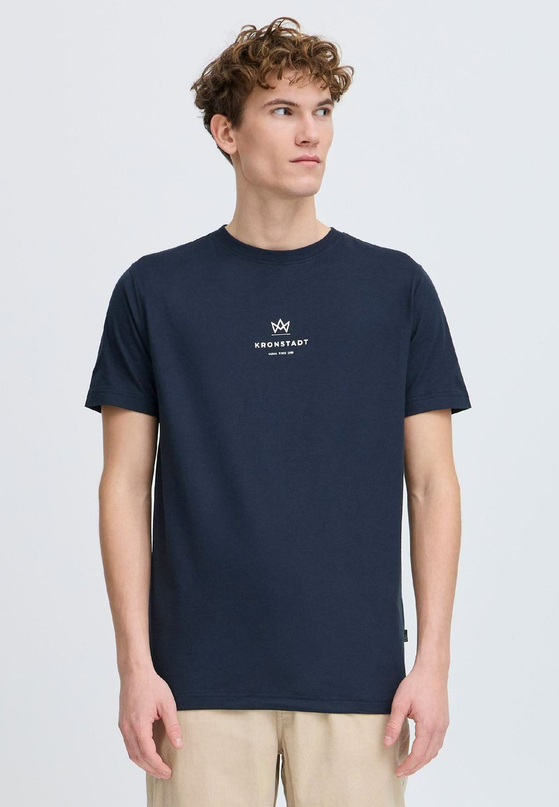 Mørkeblå bomull T-skjorte med en liten hvit logo på brystet. Korte ermer og rund hals. Glatt tekstur, klassisk passform.