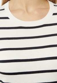 Gestreifter Pullover mit horizontalen schwarzen Streifen auf einem weißen Hintergrund, weichem Strickmaterial und runder Halslinie.