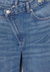 Jean en denim bleu avec poches avant, poche à monnaie pointue, passants de ceinture et fermeture par bouton métallique avec détails de couture visibles.
