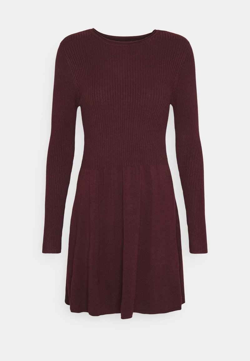 Robe bordeaux avec des manches longues, un corps côtelé et une jupe évasée. Texture lisse sur l'ensemble, décolleté rond et sans fermetures visibles.