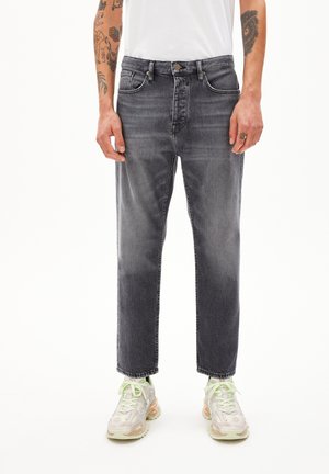 Graue Denim-Jeans mit geradem Bein, fünf Taschen und einem leicht ausgewaschenen Finish. Getragen mit gemusterter, heller Sneakers.