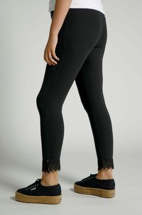 Zwarte leggings met kantafwerking aan de zoom, gemaakt van rekbaar materiaal. Gecombineerd met zwarte platform schoenen met veters.