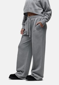 Szara, krótka bluza z miękkiego materiału oraz pasujące szerokie spodnie dresowe, z bocznymi kieszeniami i regulowanym paskiem.