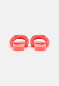 Fuzzy pink slide sandals with a smooth base, wide fluffy strap, and subtle gold accent on the upper side. Soft texture and casual design.