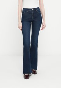 Jean flare bleu foncé avec taille haute, fabriqué en tissu denim. Comprend des poches avant, une fermeture à bouton et des détails de couture subtils.
