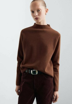 Pull à col montant marron en tissu doux, associé à un pantalon bourgogne foncé et une ceinture noire avec une boucle rectangulaire en argent.