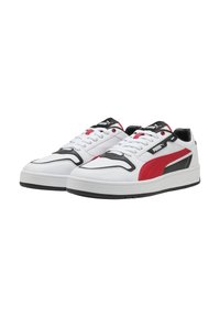 Sneakers bianchi con dettagli rossi e neri, con una tomaia in pelle liscia, punta arrotondata e suola in gomma testurizzata. Collo e linguetta imbottiti.