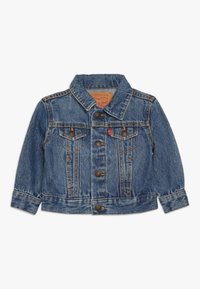 Chaqueta de mezclilla en azul medio con un collar clásico, cierre frontal de botones y dos bolsillos en el pecho. Presenta detalles cosidos y botones metálicos.