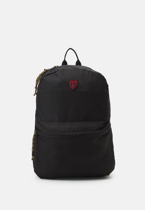 Zaino nero con manico superiore, tasca frontale con cerniera, tiralampo con motivo mimetico e piccolo emblema Polo rosso nella parte superiore frontale.