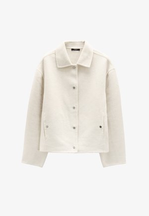 Biała polarowa kurtka z kołnierzykiem, klapkowymi guzikami, bocznymi kieszeniami i luźnym krojem. Teksturowana powierzchnia zapewnia ciepło i wygodę.