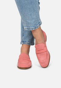Roze suede loafers met gestikte details, een lage profiel en een afgeronde neus, gedragen met opgerolde lichtblauwe spijkerbroeken.