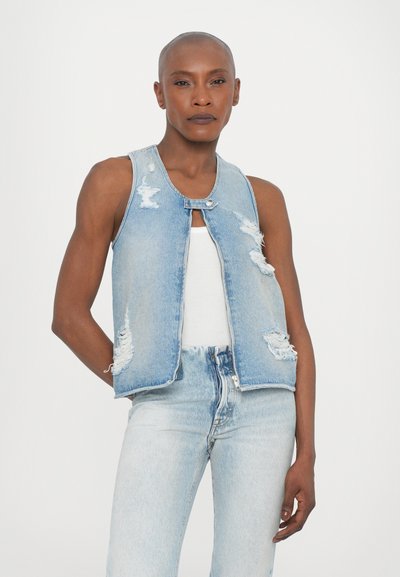 Denim brezrokavnik v svetlo modri barvi z uničenim dizajnom, ki ima zapiranje na gumbke in izreze za roke. Usklajen z visokim pasom kavbojkami.