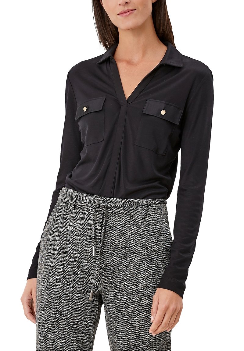 Blusa nera a maniche lunghe con scollatura a V, due tasche sul petto con bottoni dorati, abbinata a pantaloni a quadri grigio houndstooth.