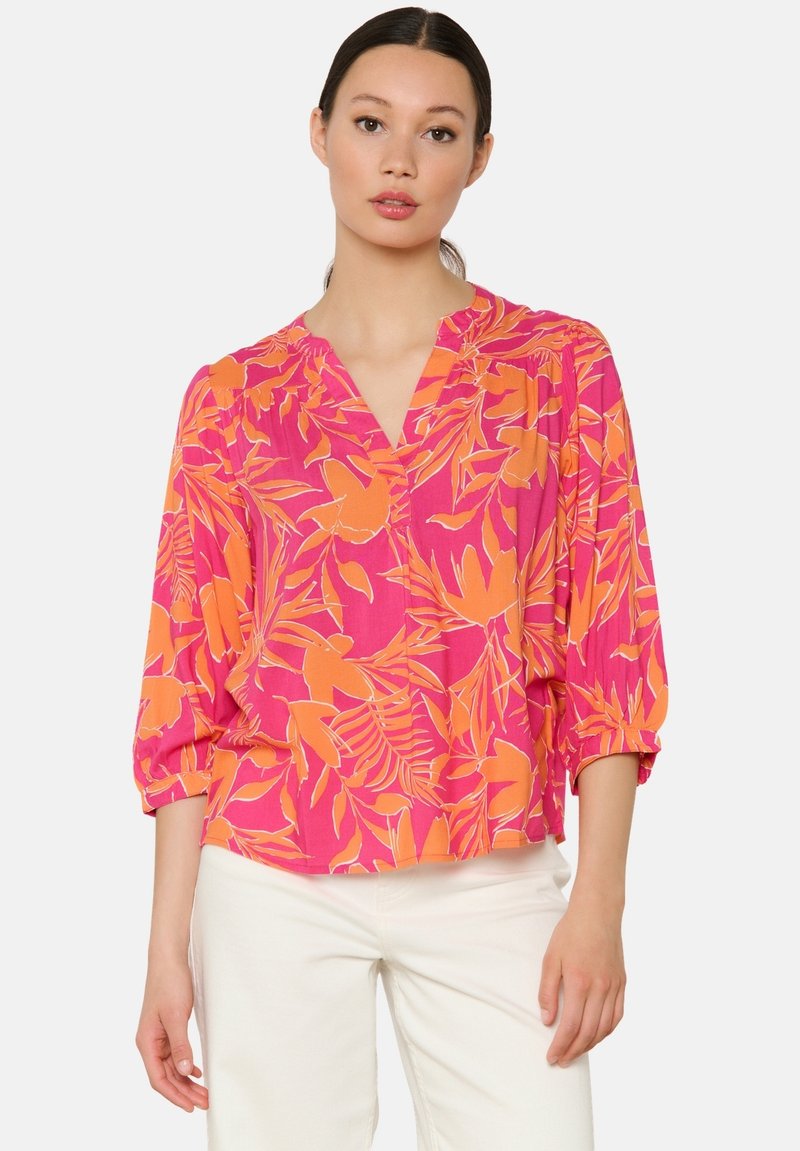 Blumenshirt in leuchtendem Pink und Orange, mit V-Ausschnitt, dreiviertel Ärmeln und lockerer Passform. Hergestellt aus leichtem Stoff.