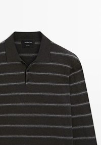 Polo shirt in lana scura con righe orizzontali grigie, dotato di colletto a coste e chiusura a tre bottoni, che mostra una texture morbida.
