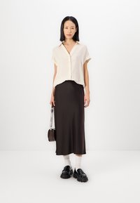 Cream-striped button-up shirt, black satin midi skirt, chunky black loafers, white socks, and small brown crossbody bag. Simple design.