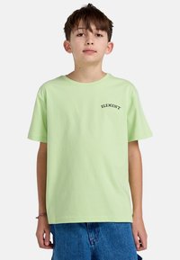 Lys grøn bomulds t-shirt med korte ærmer, prydet med "ELEMENT" logo i sort tekst på venstre brystområde, parret med blå denim shorts.