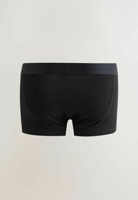 Boxer noir sans couture pour homme avec une large ceinture, vu de dos sur un fond clair uni.