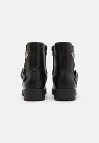 Černé kožené kotníkové boty s texturovaným povrchem, bočními zipy a dekorativním detailem ve tvaru srdce po stranách. Pevné gumové podrážky.