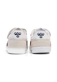 Vita och grå sneakers med en slät och mockaliknande textur, med en blå logotyp på hälen och färgglada detaljer på sidan.