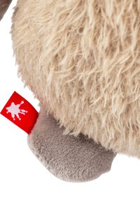 Plush toy with a soft, shaggy tan body and smooth gray underside; features a red label with a white paint splash design.