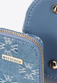 Denim-Geldbörse in Hellblau mit weißem Blumenmuster und goldenem Reißverschluss. Verfügt über einen glatten blauen Lederakzent und ein goldenes Logo-Schild.