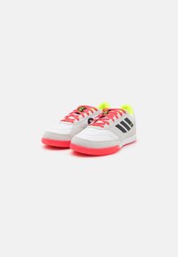 Zapatillas deportivas blancas con acentos de ante gris, suelas rosas y rayas negras. Cuentan con brillantes cordones rosas y un interior verde neón.