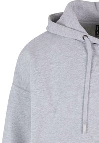 Grauer Baumwoll-Hoodie mit Kordelzug, aus strukturiertem Stoff und einer vorderen Kängurutasche. Das Design umfasst eine große, lässige Passform.