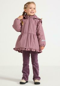 Roze gewatteerde jas met ruffle-onderkant en elastische manchetten, gecombineerd met paarse ribcordbroeken en schoenen met zwarte zolen.