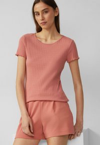 Kurzärmliges Oberteil aus weichem, rosa Rippstoff mit rundem Halsausschnitt und gewelltem Saum, kombiniert mit passenden Shorts.