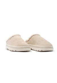 Beige mockask slip-on skor med vit pälsfoder och texturerad gummisula, med rund tå och lätt vadderad ovandel.