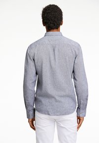 Blauwe chambray blouse met lange mouwen, knoopmanchetten en een rechte zoom. Gelaagd stof met een subtiel patroon, rugpaneel detail.
