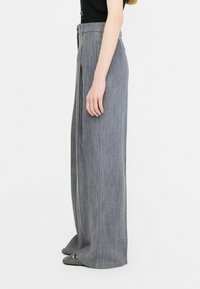 Light gray wide-leg trousers with a high waist, featuring a smooth texture and subtle pleats, paired with patterned pointed flats.
