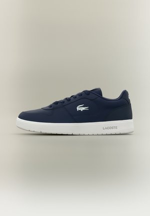 Marineblauwe lage sneaker met witte zool, vetersluiting en wit Lacoste krokodillenlogo aan de zijkant.