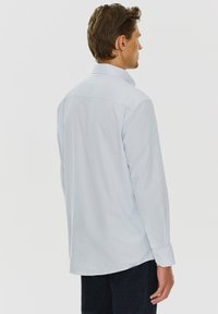 Jasnoniebieska koszula z długim rękawem, wykonana z gładkiego połączenia bawełny, z delikatnym wzorem. Z kołnierzykiem zapinanym na guziki i mankietami. Dopasowany krój, prosty dół.