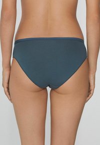 Tmavě modré bavlněné bikiny s nízkým pasem, hladkým povrchem, elastickým pasem a minimalistickým střihem. Bez viditelných vzorů nebo log.