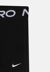 Shorts de sport noirs avec une large taille élastique arborant un logo blanc, un design épuré, une texture lisse et des coutures discrètes.