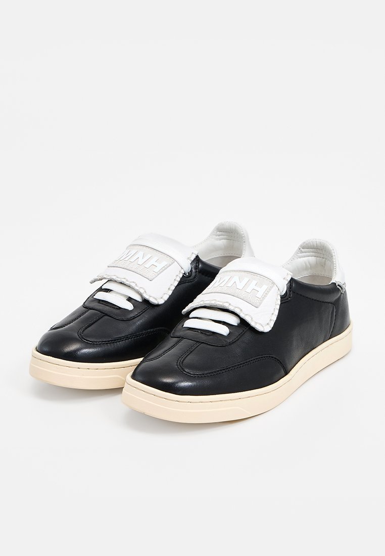 Czarne skórzane sneakersy z białą, wyściełaną językiem i sznurowadłami. Posiadają beżową gumową podeszwę i gładką fakturę, oferując retro design.