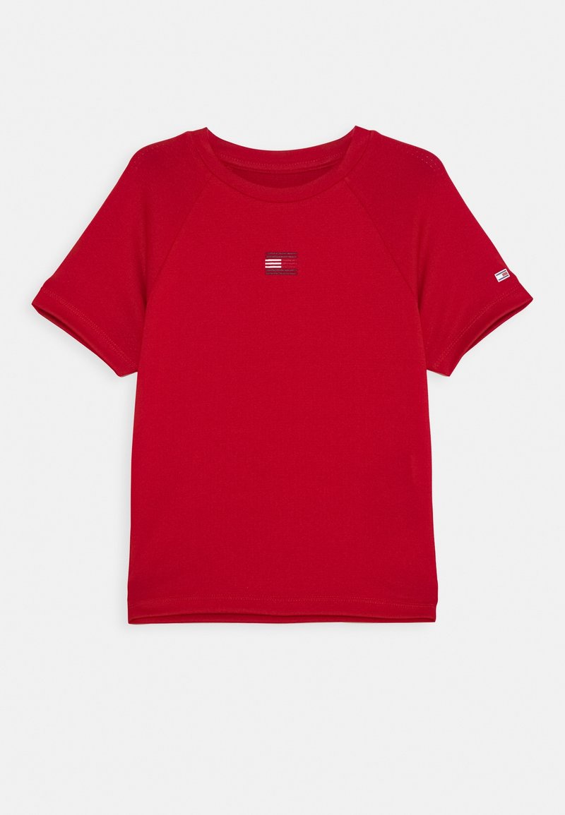 Punainen puuvillapaita, jossa on lyhyet raglan-hihat, pyöreä pääntie ja pieni brodeerattu logo keskellä. Sujuva tekstuuri ja rento muotoilu.