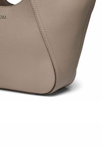 Bolso de cuero beige con un acabado texturizado, que presenta líneas limpias, una silueta curva y costuras de contraste a lo largo de las costuras.